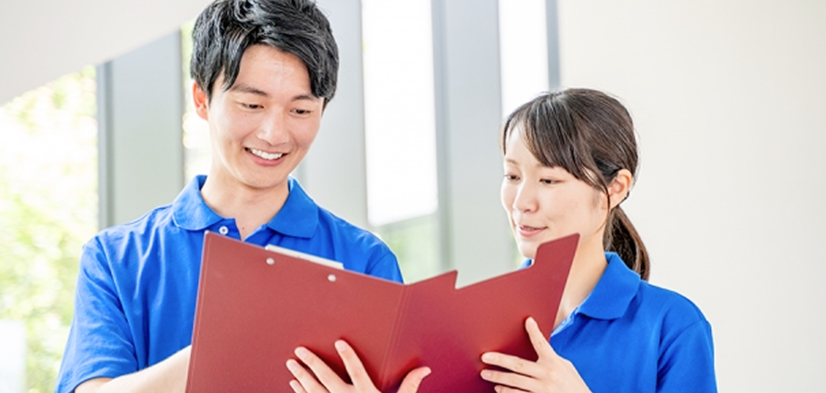 施設のスタッフの男女二人がファイルを見ながら笑顔で話している様子